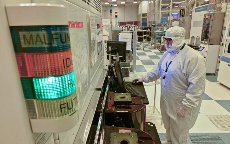 a person wearing a bunny suit in a cleanroom suit looks a monitor