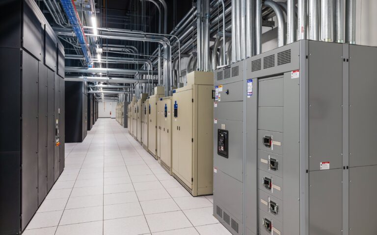 industrial server room with grey cabinets and extensive overhead piping